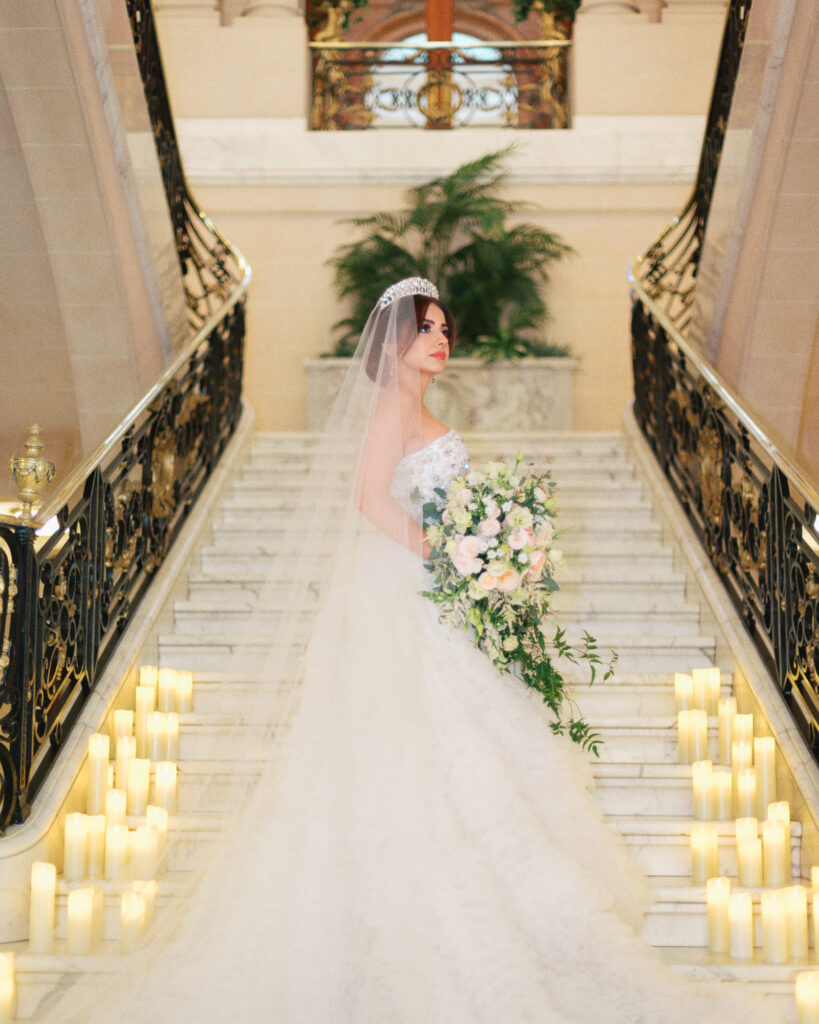 A bride stands of the staircase of the Perry Belmont House